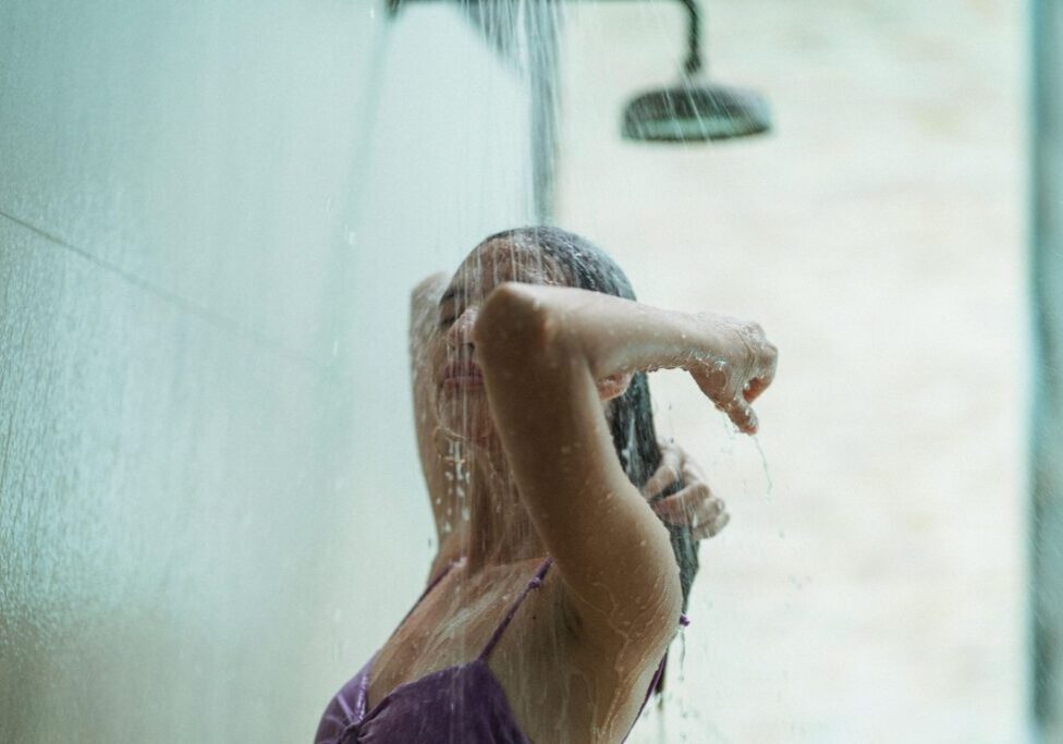 Person enjoying outdoor shower in swimwear